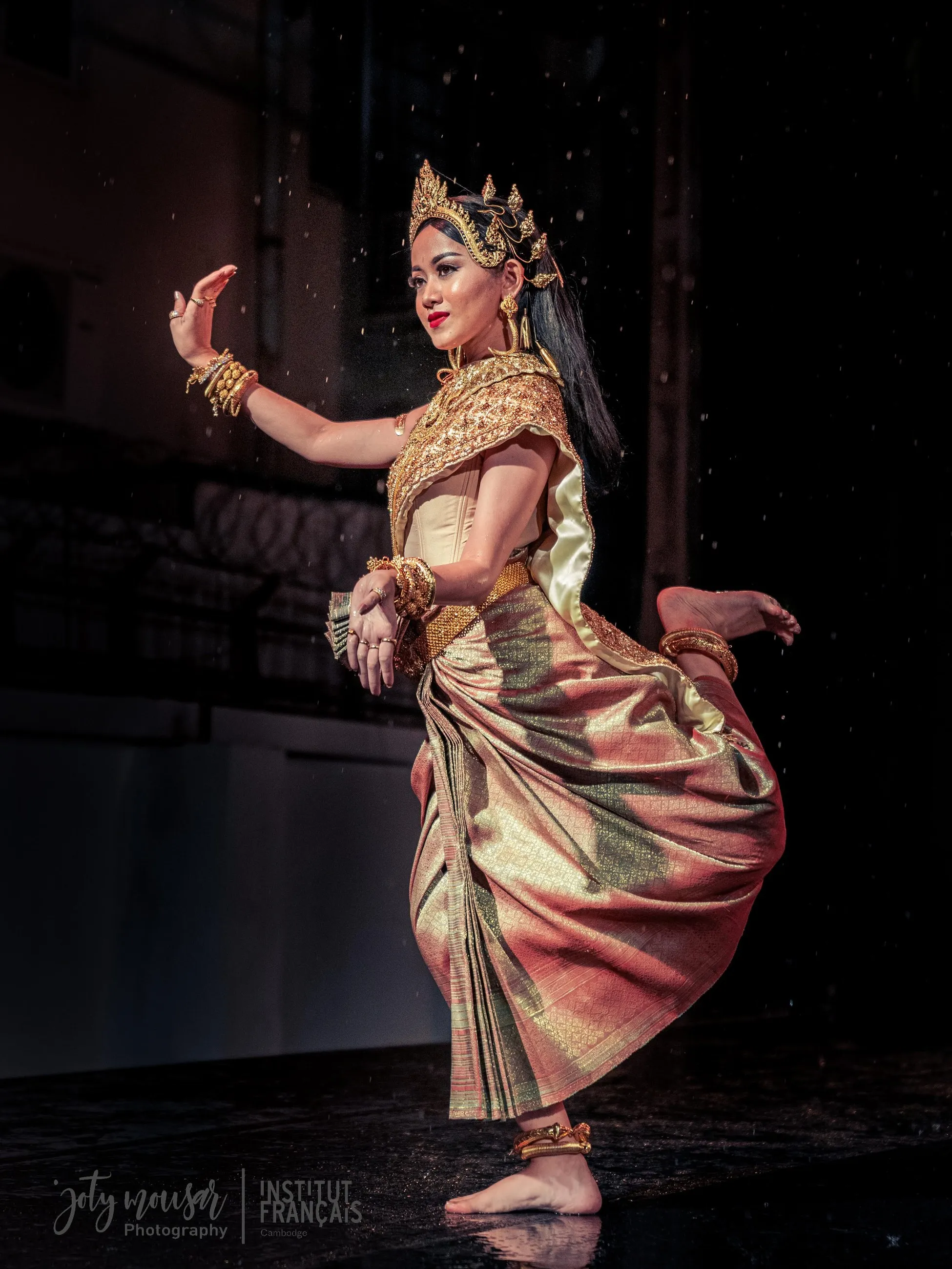 Serei Van Kosaun dancing in falling rain on a dark stage